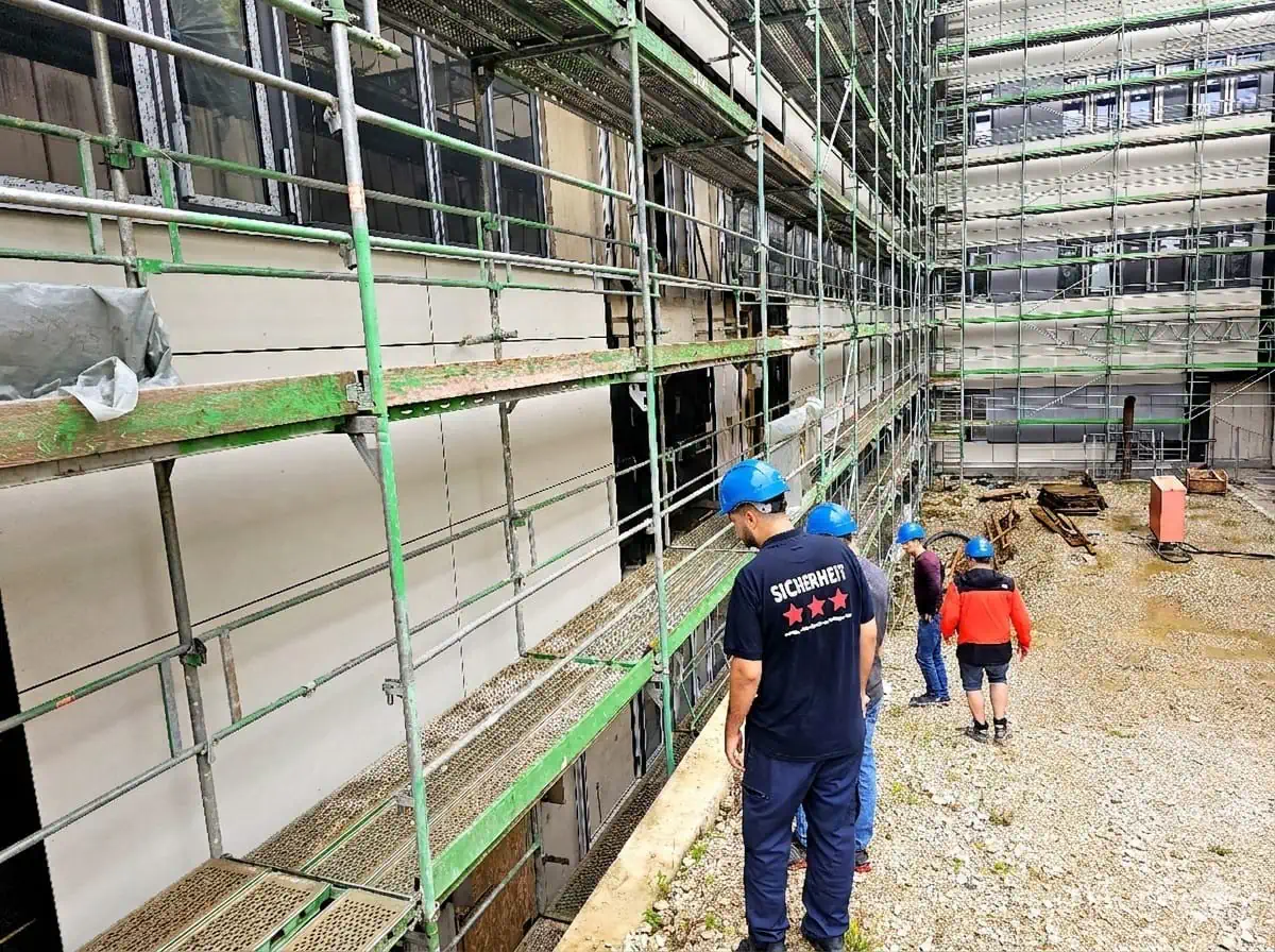 Sicherheitsmitarbeiter kontrolliert eine Baustelle mit Gerüst
