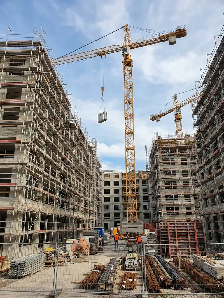 Große Baustelle mit Kränen und Rohbauten, gesichert durch die Baustellenbewachung
