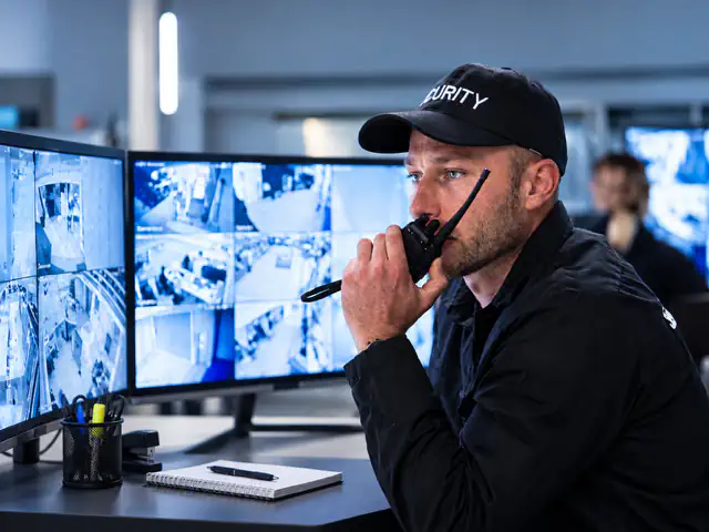Sicherheitsmitarbeiter mit Funkgerät in der Notruf- und Serviceleitstelle der Eichinger Sicherheit und Service GmbH für die 24/7-Überwachung