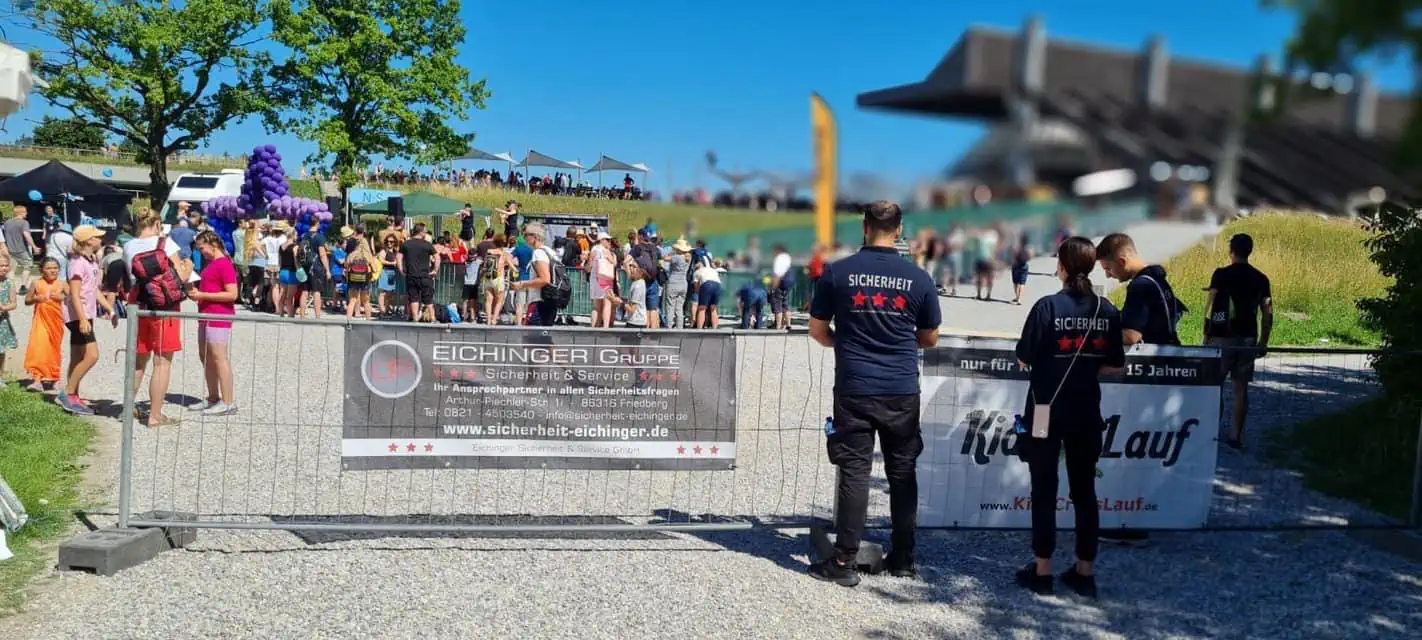 Eichinger Sicherheitsmitarbeiter an einer Absperrung mit Firmenbanner bei einer öffentlichen Laufveranstaltung