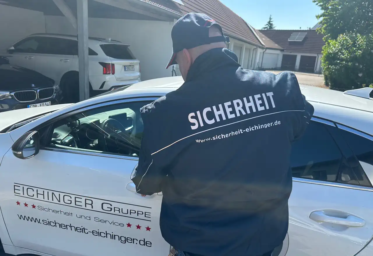 Sicherheitsmitarbeiter der Eichinger Sicherheit und Service GmbH neben einem Einsatzfahrzeug