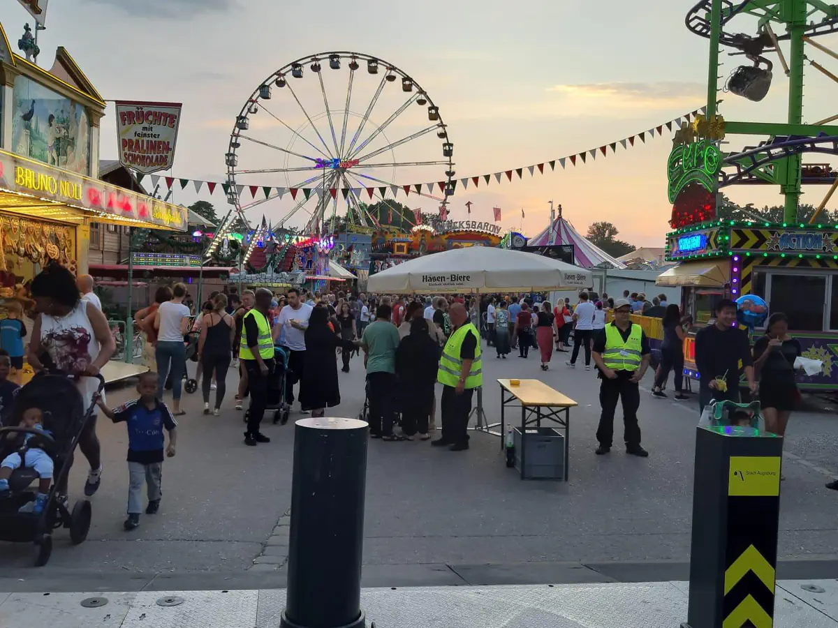 Einlassbereich eines Volksfests mit Besuchern und Sicherheitskräften für die Event-Security
